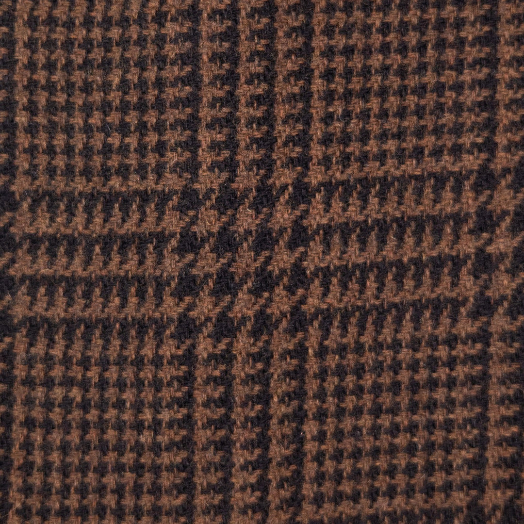 A close-up of a woven fabric texture featuring a brown and black houndstooth pattern with subtle plaid block details.