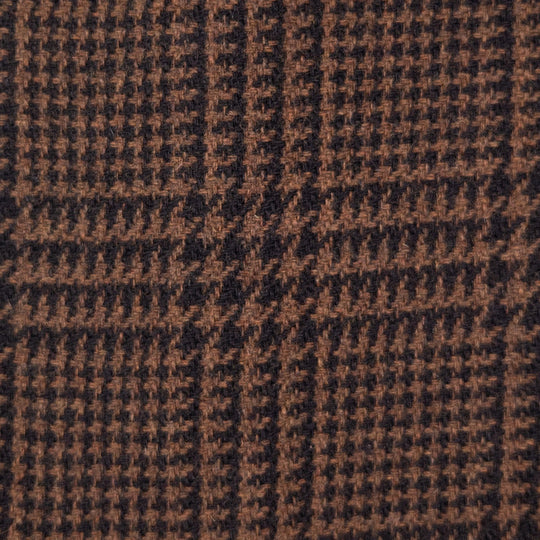 A close-up of a woven fabric texture featuring a brown and black houndstooth pattern with subtle plaid block details.