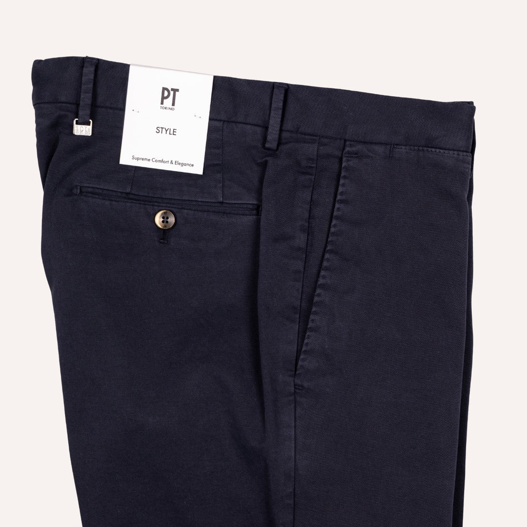 Close-up of dark navy trousers showing the waistband, belt loops, back pocket, and a white PT Style brand tag.