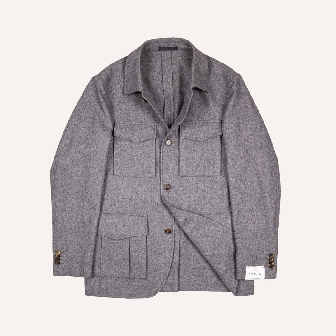 A gray textured wool-blend utility jacket with a collar, button front, and multiple front pockets, displayed flat against a light cream background.