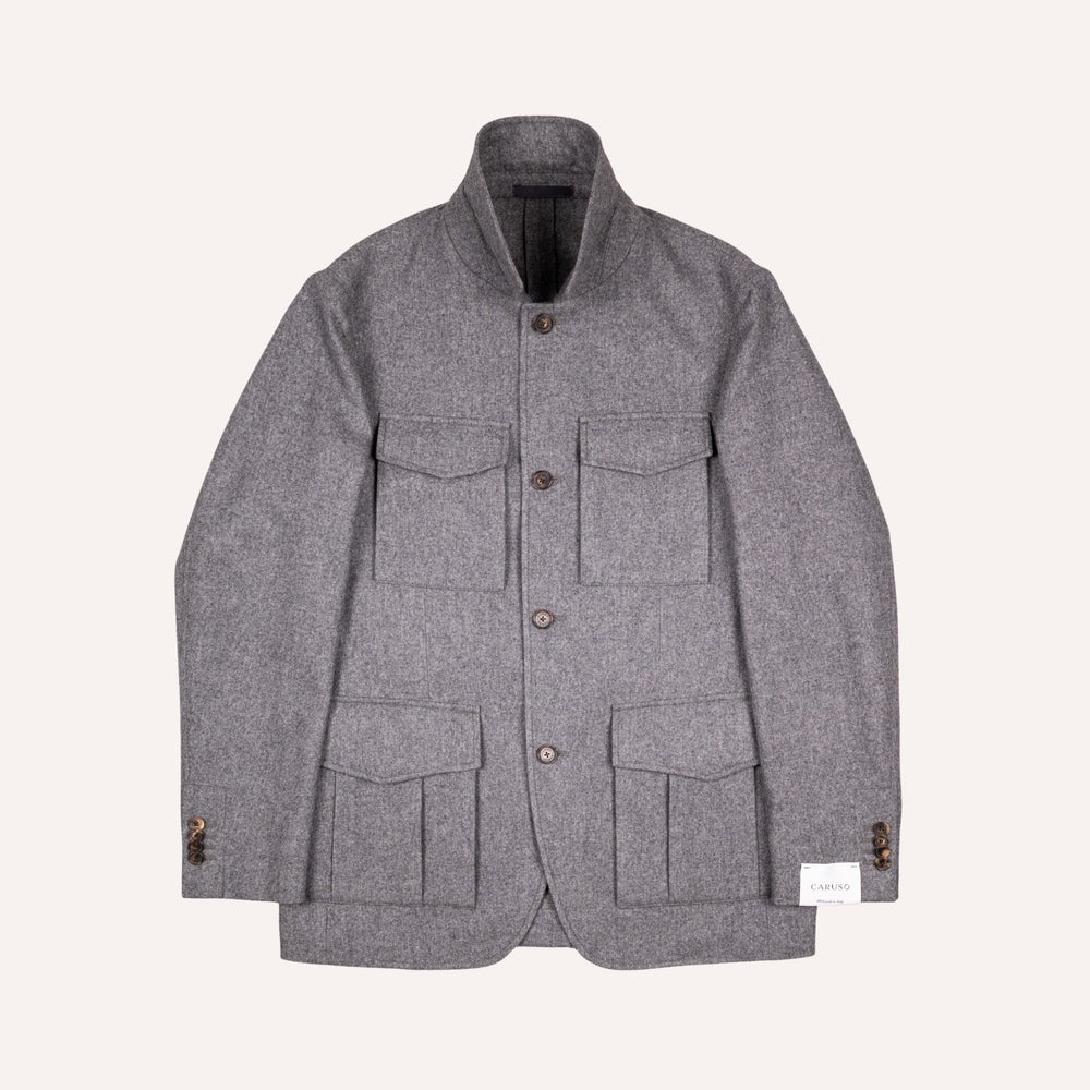 A gray textured wool jacket with a stand collar, button closure, and four front flap pockets, displayed flat against a light cream background.