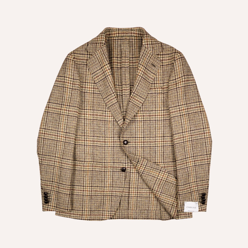 A men's single-breasted blazer in a beige and brown plaid pattern, featuring notch lapels, two dark buttons, and a small white brand label on the lower right front hem, displayed against a solid off-white background.