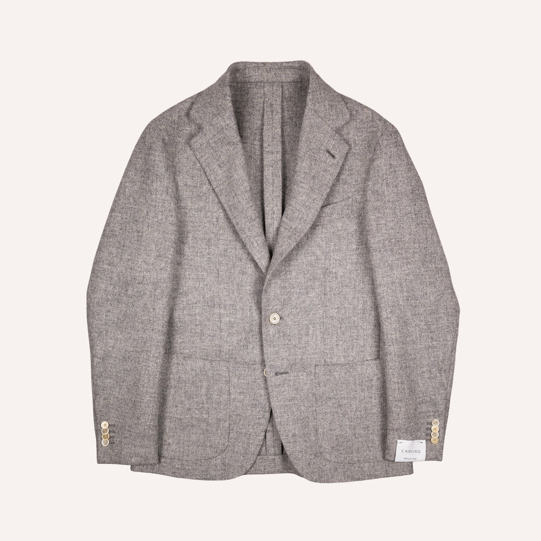 A light gray textured wool blazer with a two-button front, notched lapels, and cream button accents on the cuffs, displayed flat against a light cream background.