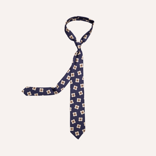 A navy blue necktie with a repeating beige and white geometric pattern, displayed on a solid off-white background.