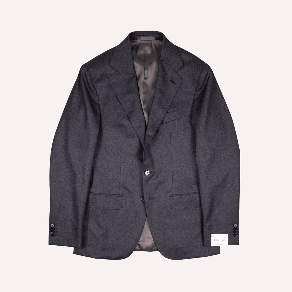 A dark charcoal gray textured wool blazer jacket with a single button closure, laid flat against a light cream background.