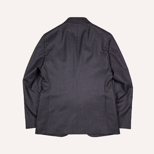 A dark charcoal gray blazer shown from the back, laid flat against a light cream background.