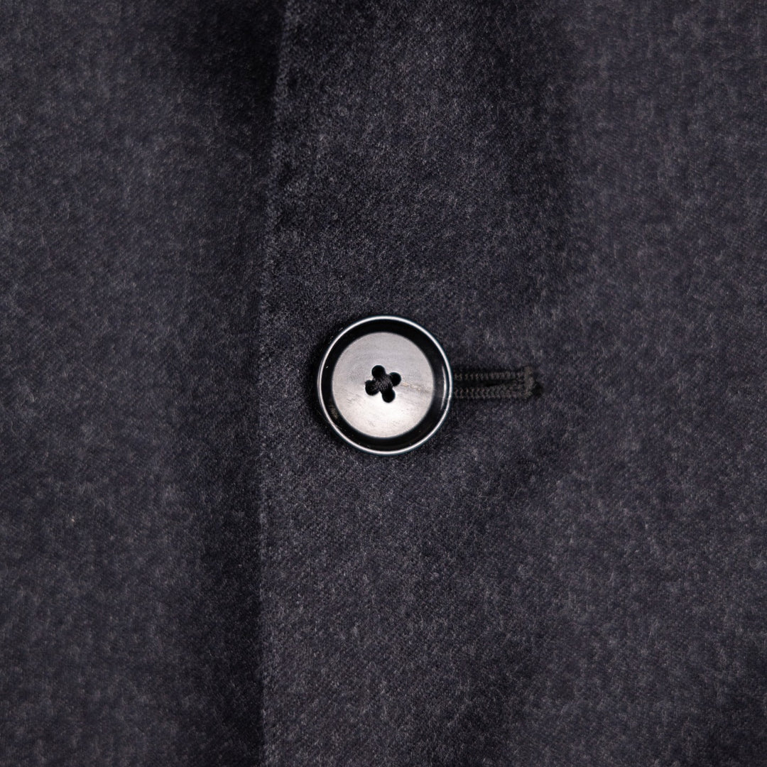 Close-up of a dark charcoal gray wool fabric with a single button 