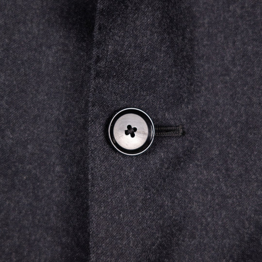 Close-up of a dark charcoal gray wool fabric with a single button 