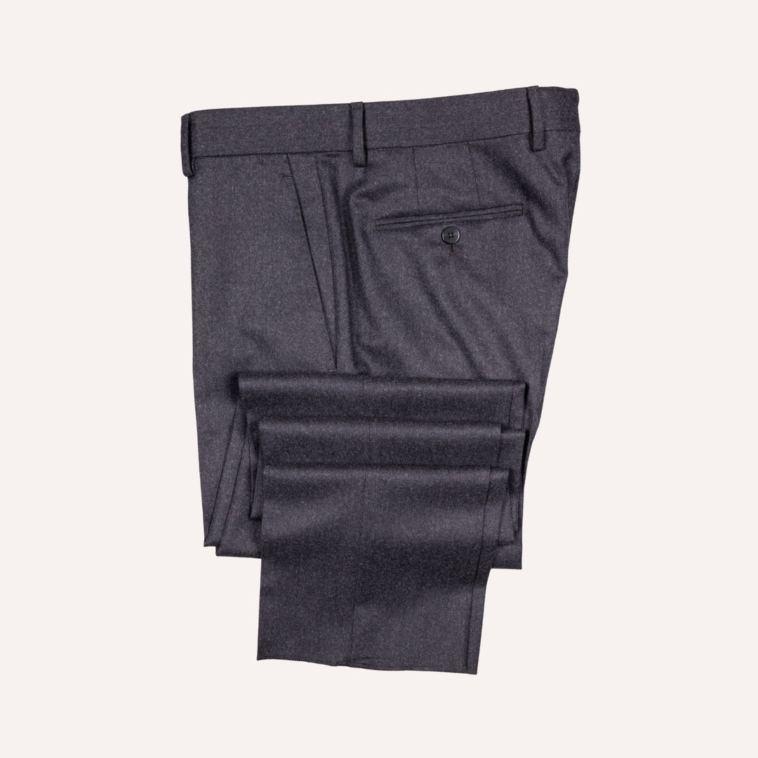 Dark charcoal gray dress pants folded neatly on a light cream background, showing the back waistband, belt loops, and a rear welt pocket.