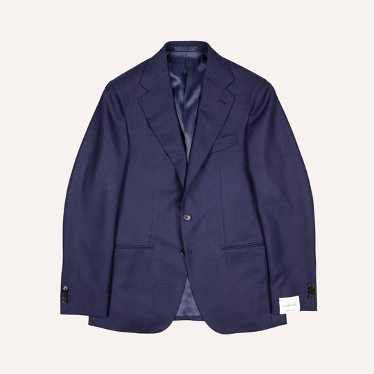 A navy blue single-breasted blazer with notch lapels, a two-button closure, and flap pockets, displayed flat against a light cream background.