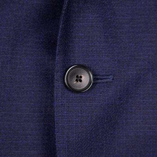 Close-up of a dark navy blue textured knit fabric with a single black button on the front.