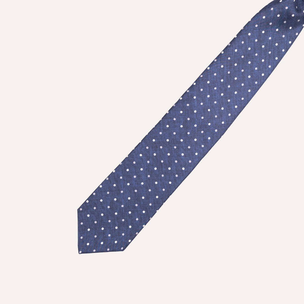 A navy blue necktie with a white polka dot pattern, laid diagonally on a light cream background.