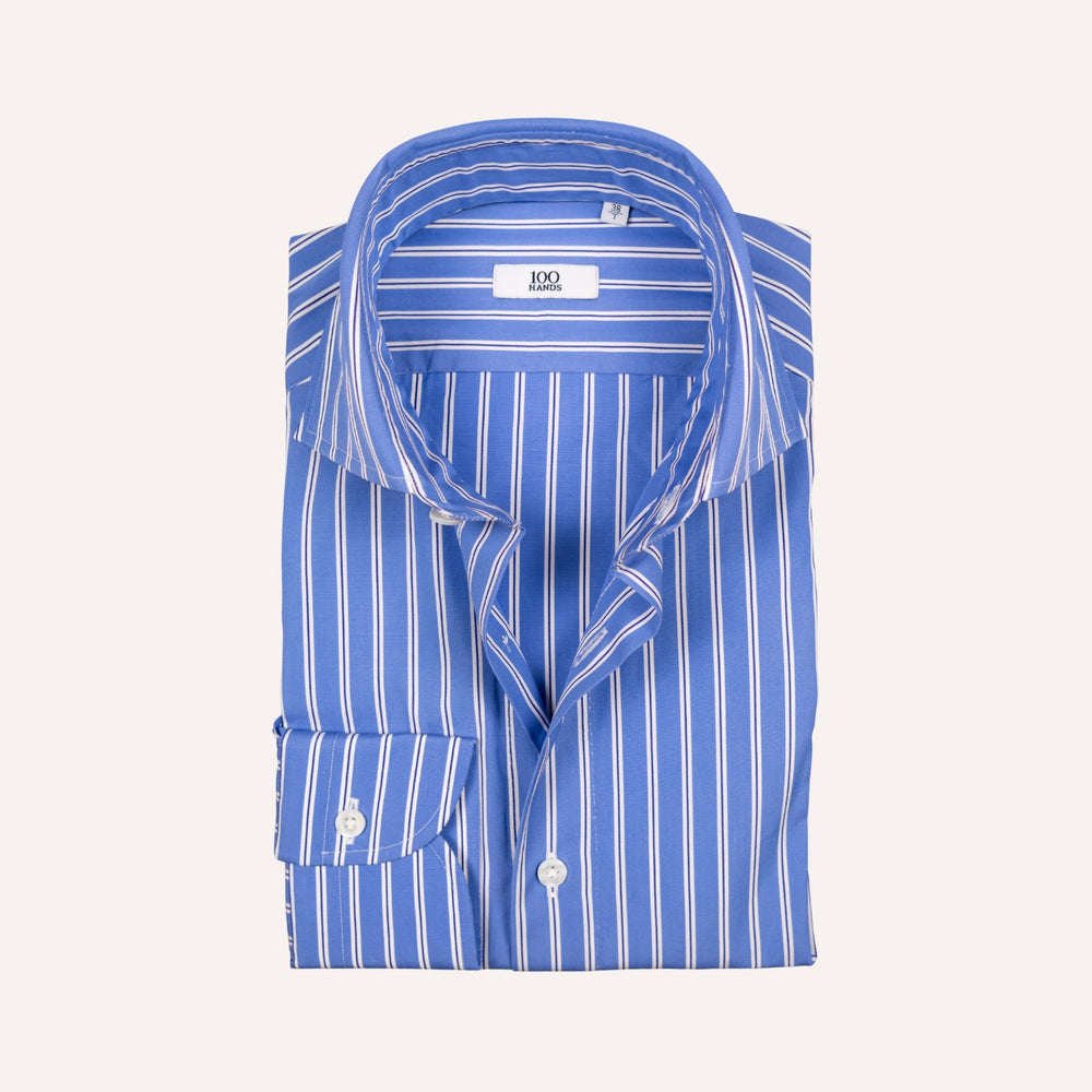 A folded blue and white vertically striped dress shirt with a spread collar and a visible neck label reading '100 Hands'.