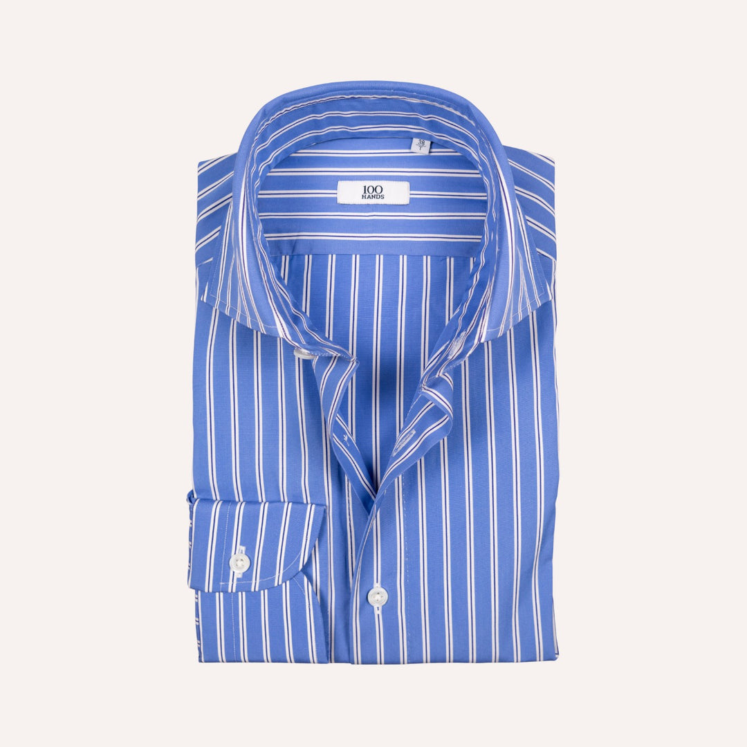 A folded blue and white vertically striped dress shirt with a spread collar and a visible neck label reading '100 Hands'.
