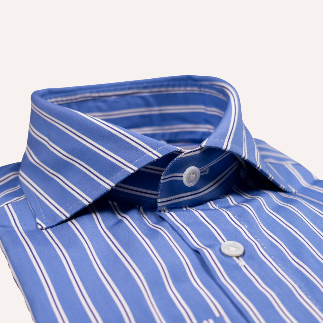 A close-up of a blue and white striped dress shirt collar with white buttons, shown on a clean off-white background.