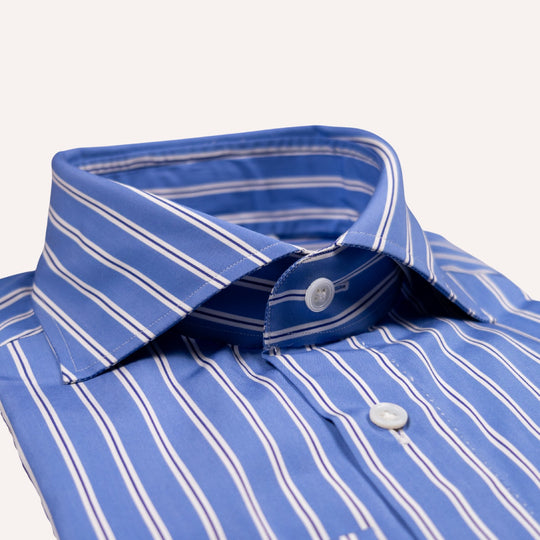 A close-up of a blue and white striped dress shirt collar with white buttons, shown on a clean off-white background.