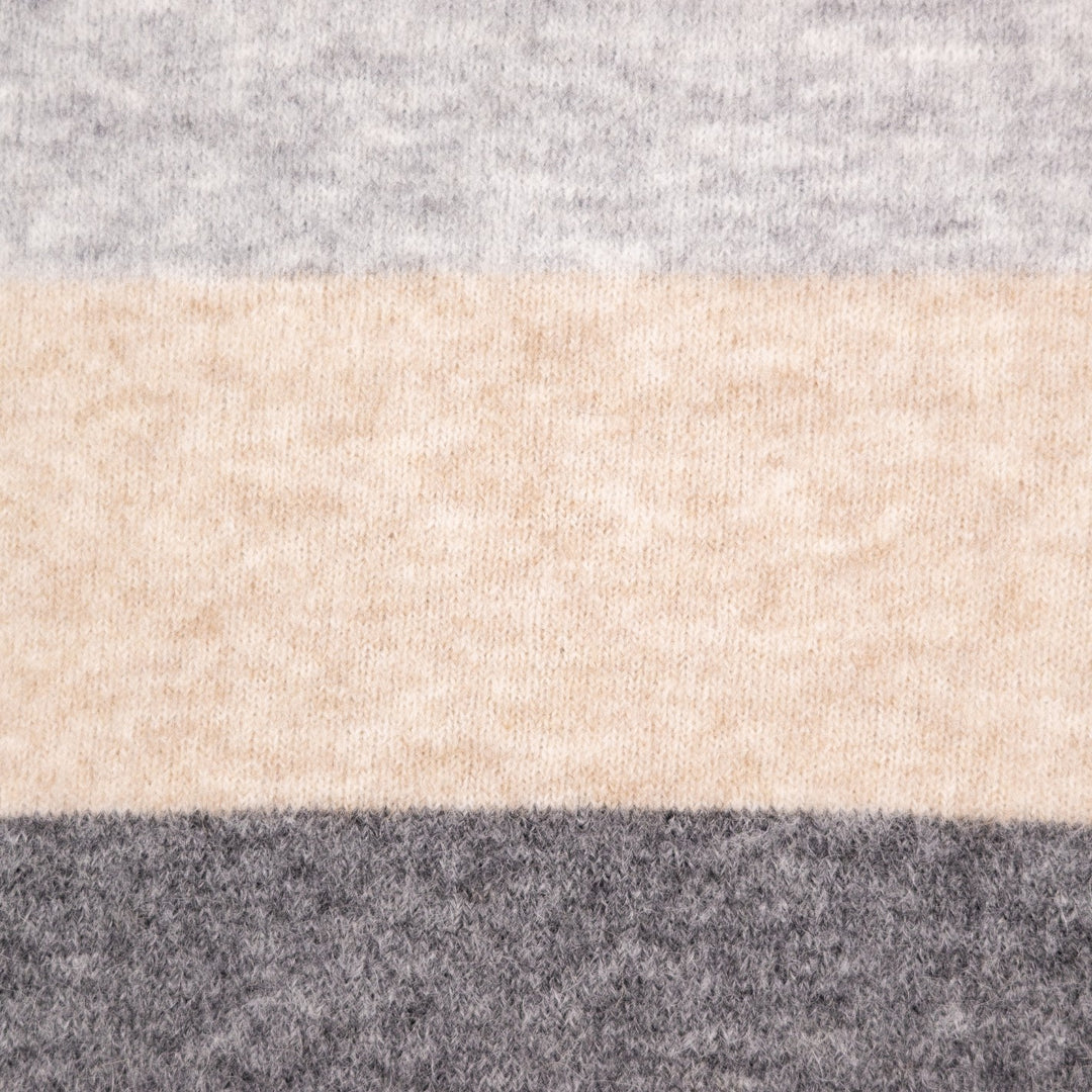 A close-up of a soft knit fabric with horizontal stripes in light gray, warm beige, and dark charcoal gray.