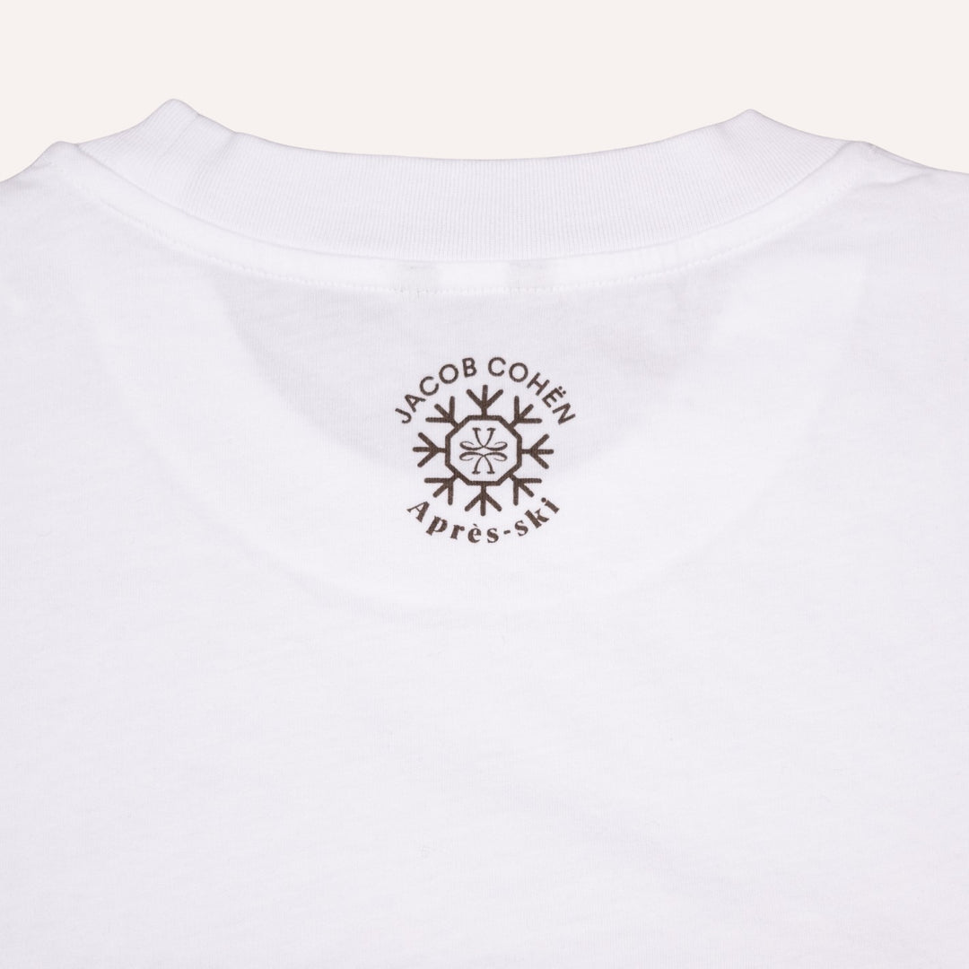 Close-up of the back of a white cotton t-shirt, featuring a dark brown circular graphic print with the text 'JACOB COHEN' and 'Après-ski' surrounding a snowflake design.