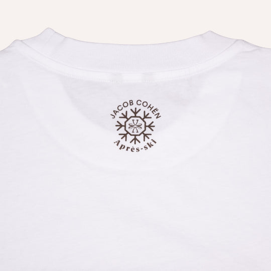 Close-up of the back of a white cotton t-shirt, featuring a dark brown circular graphic print with the text 'JACOB COHEN' and 'Après-ski' surrounding a snowflake design.