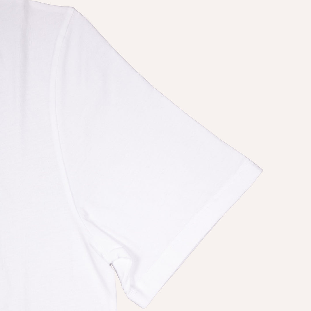 A close-up of a plain white short-sleeve t-shirt showing the sleeve and shoulder seam, set against a solid off-white background.
