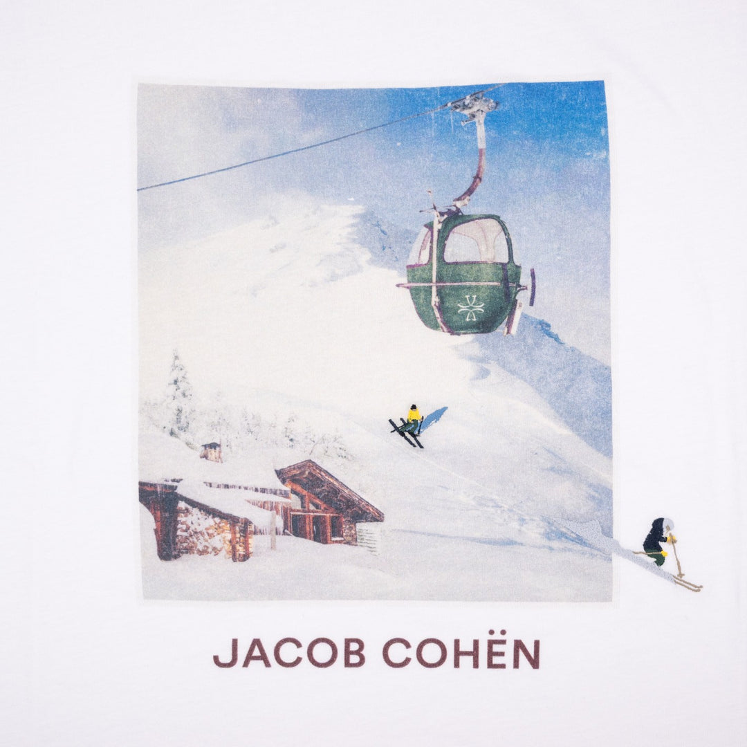 A white square art print or poster featuring a snowy mountain scene with a green gondola, skiers, and a small cabin, with the text 'JACOB COHËN' printed below in dark red. The print is photographed against a white background.