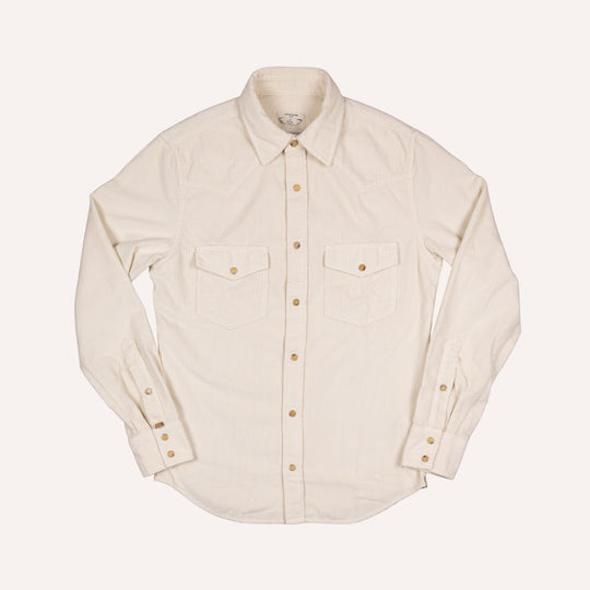 An off-white long-sleeve corduroy western shirt with two chest flap pockets and brass buttons, laid flat against a light cream background.