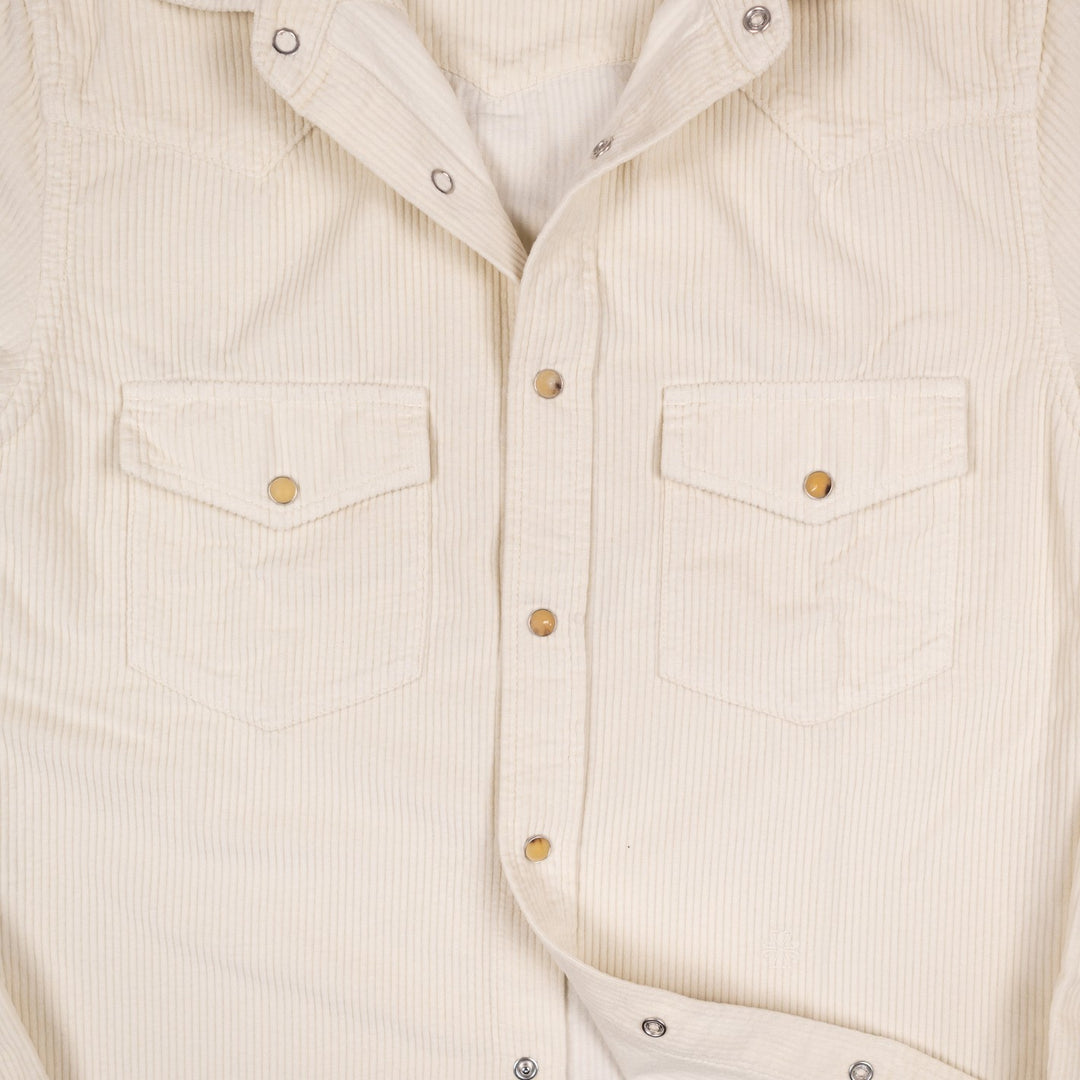Close-up of an off-white corduroy western shirt with two chest flap pockets and  snap buttons.
