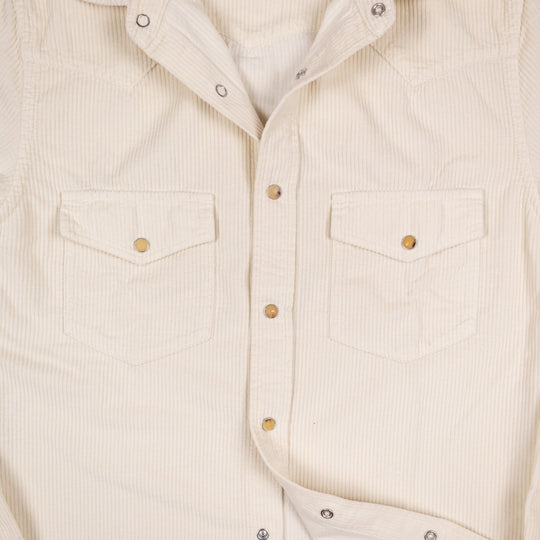 Close-up of an off-white corduroy western shirt with two chest flap pockets and  snap buttons.