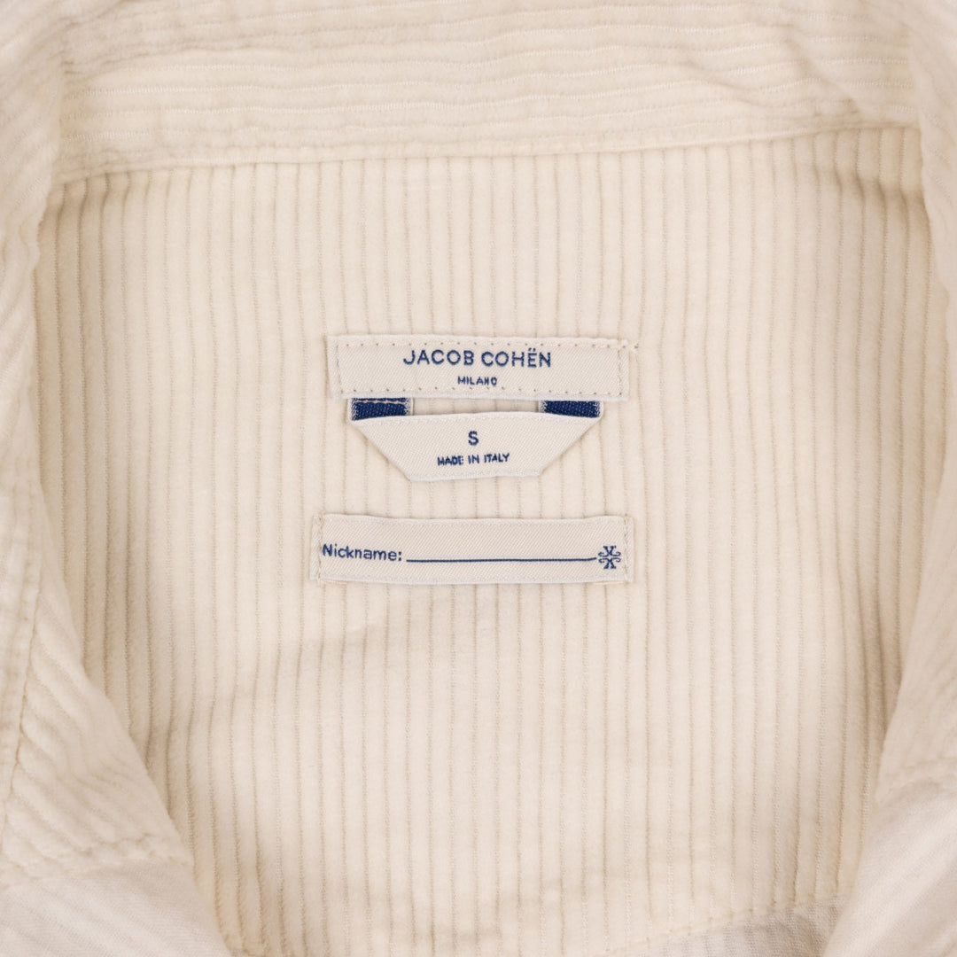 Close-up of the inside neck label of a cream-colored ribbed cotton garment, showing the brand 'JACOB COHËN' and size 'S'.