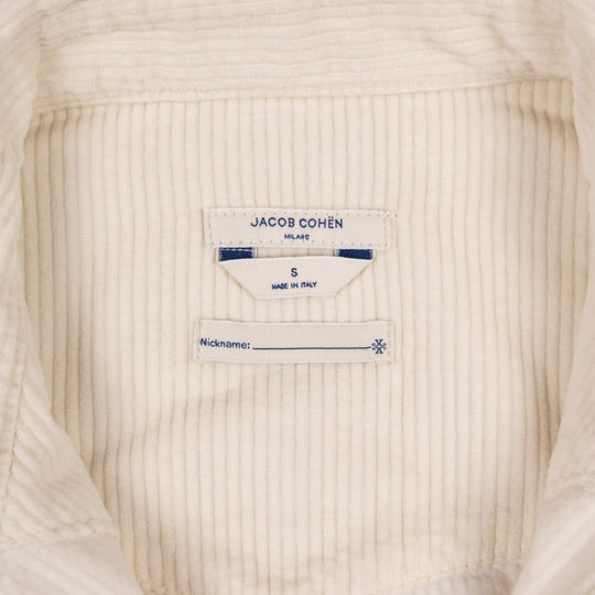 Close-up of the inside neck label of a cream-colored ribbed cotton garment, showing the brand 'JACOB COHËN' and size 'S'.
