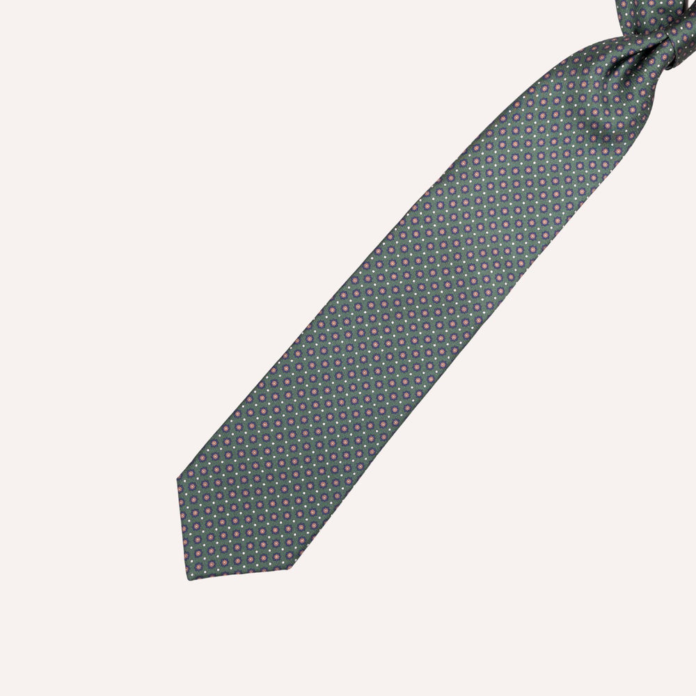 A dark green necktie with a small repeating pattern of pink and white dots, shown tied at the top against a solid off-white background.