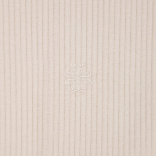 Close-up of a ribbed knit fabric in a light warm beige or cream tone, with a subtle tonal embroidered logo at the center.