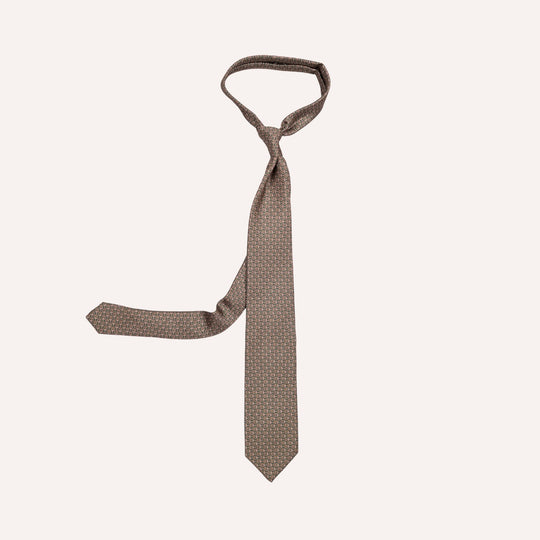 A brown necktie with a small geometric pattern, tied in a knot and displayed against a solid off-white background.