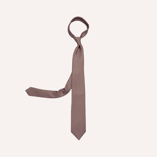 A men's necktie with a brown base and a small orange geometric pattern, tied in a standard knot and displayed against a solid off-white background.