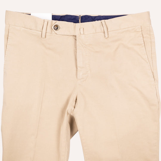 Beige chino pants shown flat against a light background, featuring a button closure, belt loops, and a dark navy interior waistband.