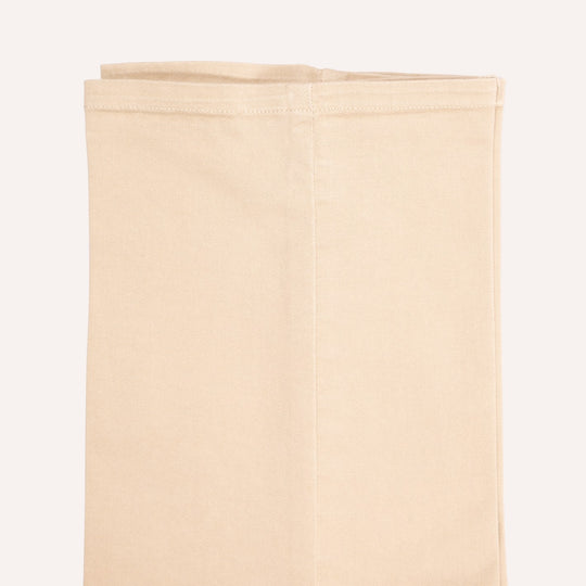 A folded beige trouser, shown against a solid off-white background.