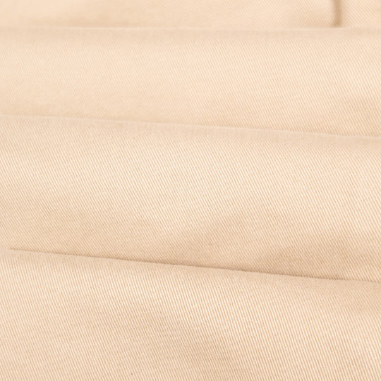 A close-up of folded beige fabric with a fine diagonal twill texture.