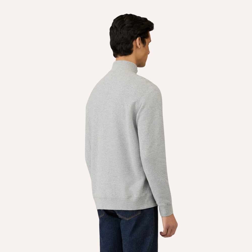 A man wearing a light gray half-zip mock neck sweater, shown from a rear three-quarter angle against a solid off-white background.