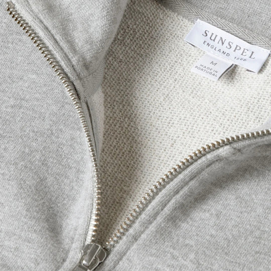 Close-up of a light heather gray zip-up hoodie showing the inner collar, silver zipper, and a white SUNSPEL brand label.