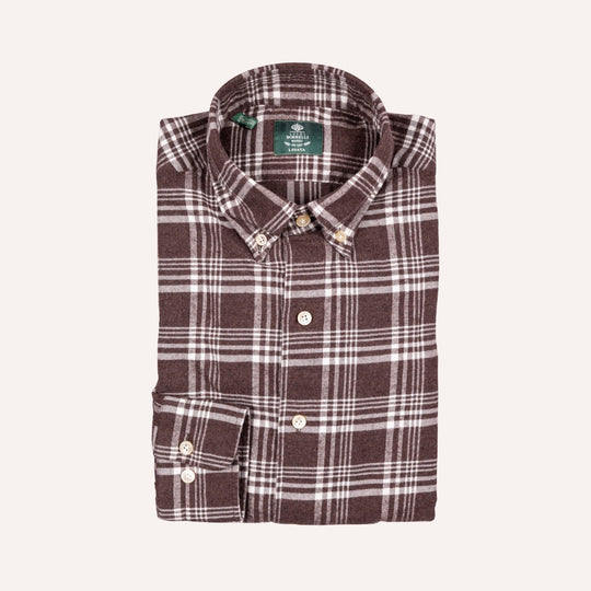 A folded brown and white plaid button-down shirt with a green neck label, displayed on a light cream background.