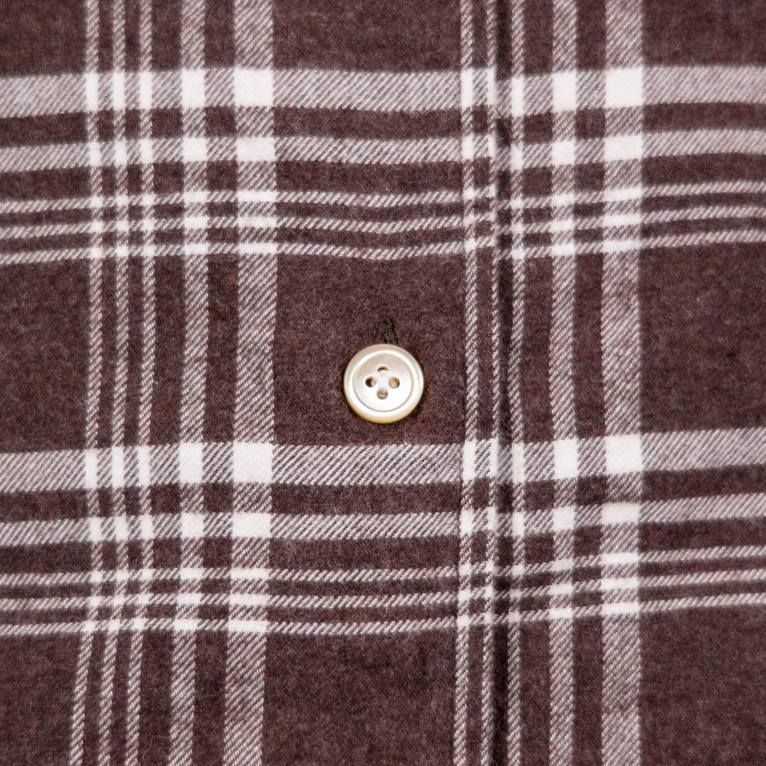 Close-up of a brown plaid fabric with white and gray stripes and a single light-colored button.