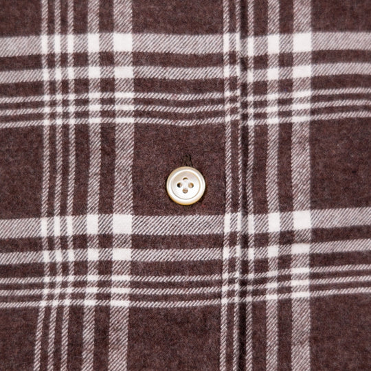 Close-up of a brown plaid fabric with white and gray stripes and a single light-colored button.