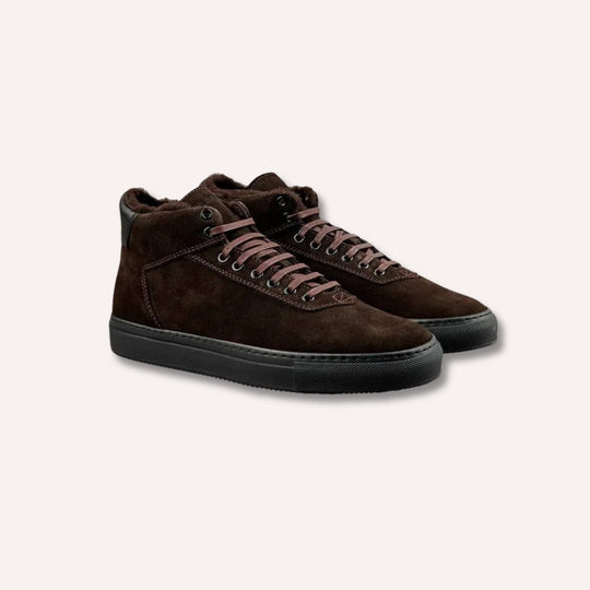 A pair of dark brown suede high-top sneakers with matching brown laces and black soles, displayed on a light beige background.